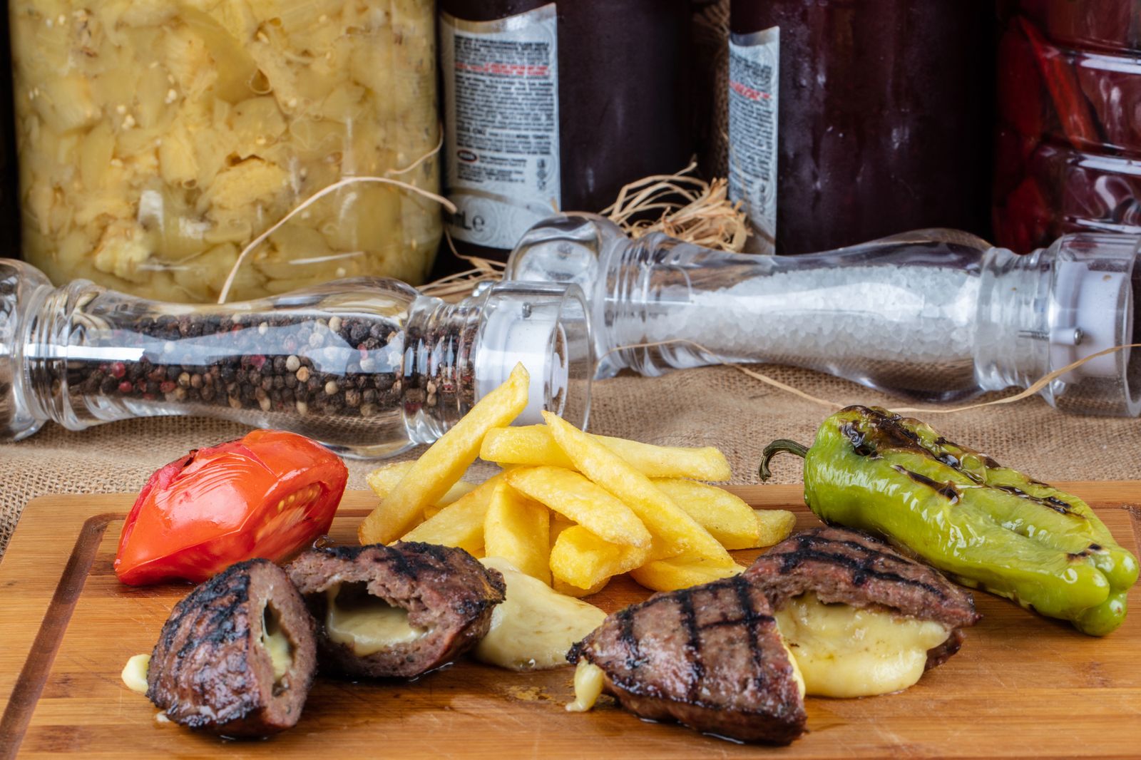 Gegrillte Fleischlaberl mit Käsefüllung, Pommes, Paradeiser und Pfefferoni